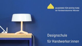Das Bild zeigt eine moderne Tischlampe auf einem Holztisch vor einer blauen Wand. Daneben stehen Werkzeuge und Materialien für Handwerker:innen.